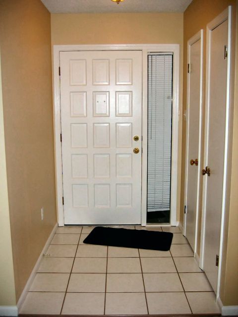 1985 Ford LTD Crown Victoria - A view of a home's interior entryway, a white paneled door, a side window with blinds, and tiled flooring.