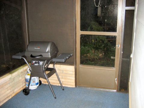 1985 Ford LTD Crown Victoria - Gas grill and propane tank on a screened-in porch next to a door.