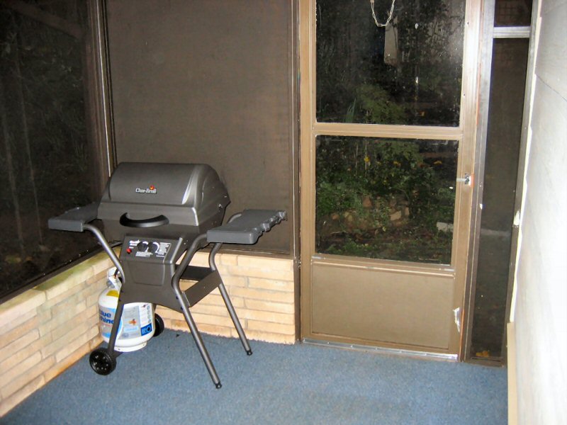 Char-Broil gas grill with propane tank on a screened porch