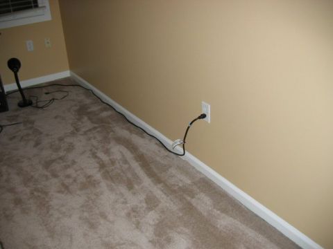 1985 Ford LTD Crown Victoria - An electrical cord runs along the baseboard of a carpeted room.