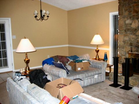 1985 Ford LTD Crown Victoria - A cluttered living room scene features two sofas, lamps, and a large stone fireplace, suggesting a home environment.