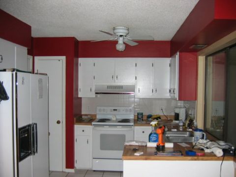1985 Ford LTD Crown Victoria - A view of a kitchen with white appliances and cabinets, contrasted by red walls.