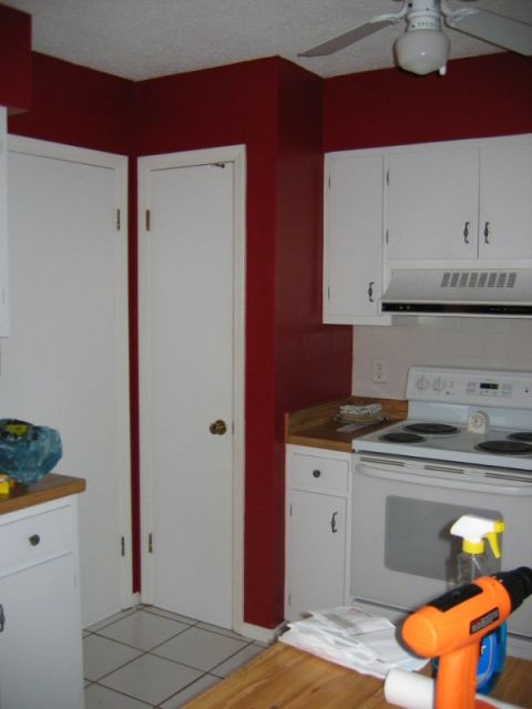 1985 Ford LTD Crown Victoria - A view of a kitchen red walls, white cabinetry, and a white electric stove with an overhead vent.