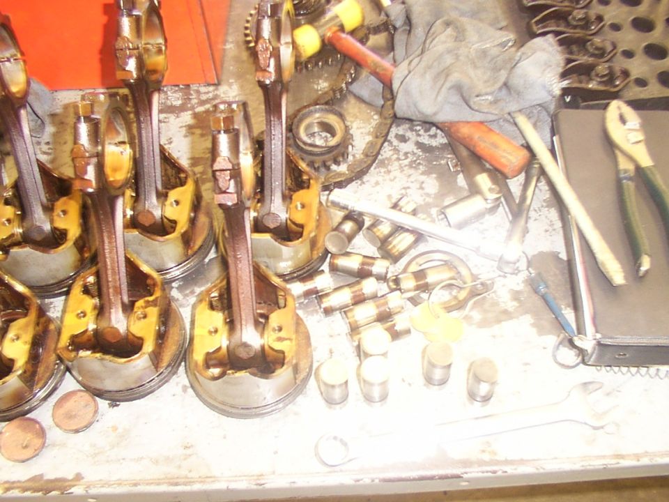 Pistons and connecting rods laid out on a workbench with tools