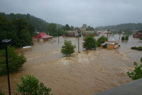 1985 Ford LTD Crown Victoria - A town is submerged in floodwaters, with only the tops of buildings and trees visible.