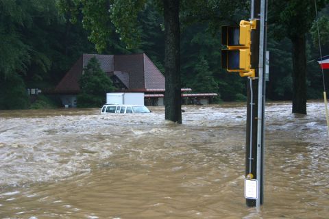 1985 Ford LTD Crown Victoria - A white van is submerged in floodwaters near a house during a flood event.