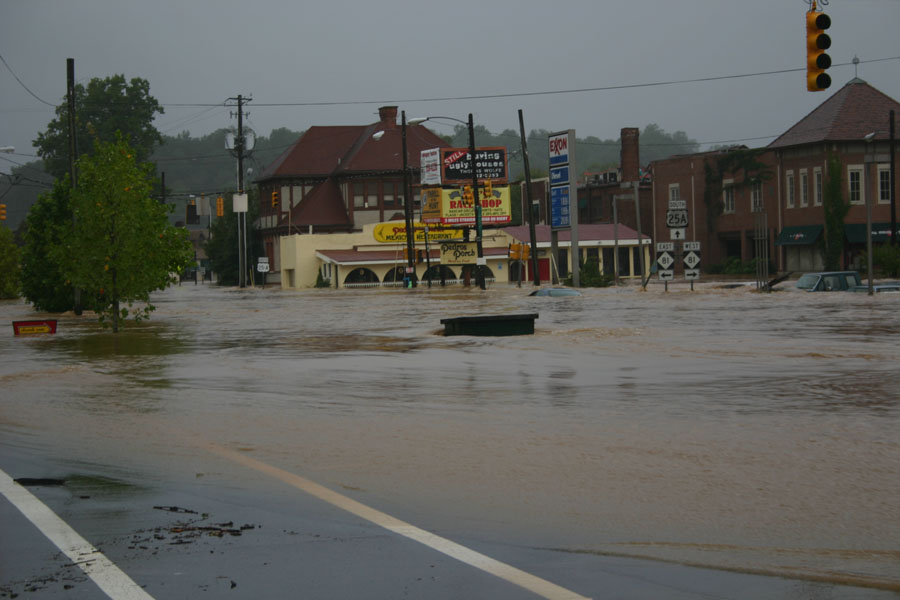 Flooded street with submerged cars and buildings, including a Bay Shop sign