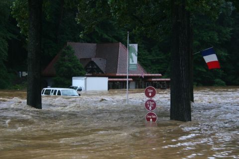 1985 Ford LTD Crown Victoria - Floodwaters surround vehicles and a building, with signs indicating tickets and group sales.