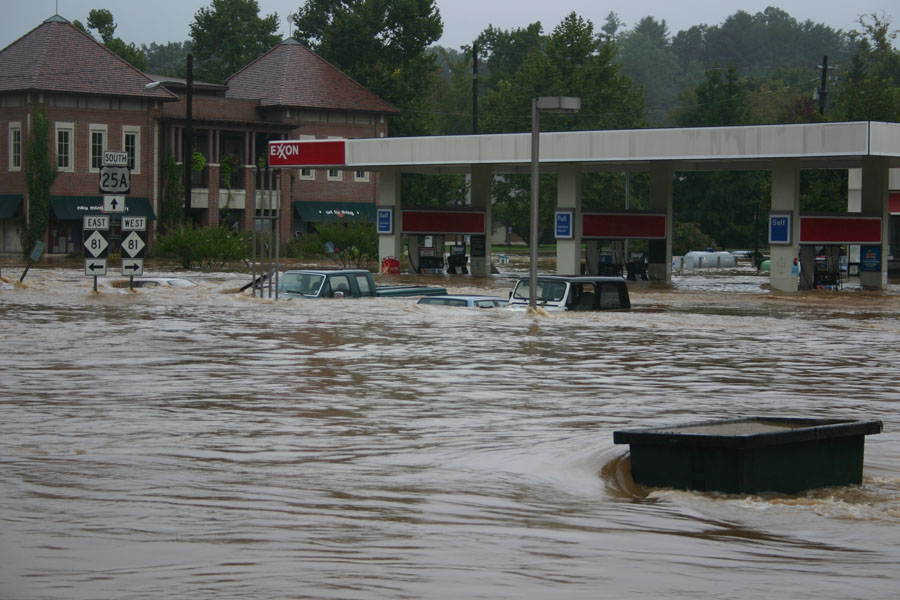 Flooded vehicles submerged in brown water at an Exxon gas station