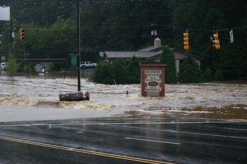 1985 Ford LTD Crown Victoria - A white SUV is seen partially submerged in floodwaters on a street near the Biltmore Estate sign.