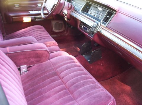 1991 Ford Crown Victoria LTD - The plush maroon velour interior of a 1991 Ford Crown Victoria LTD features a classic dashboard and comfortable seating.