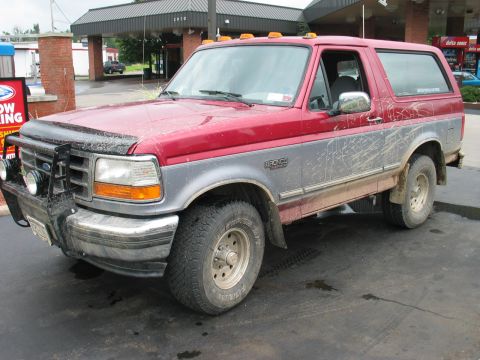 1995 Ford Bronco - This muddy Ford Bronco is parked outside a building with a covered entrance.