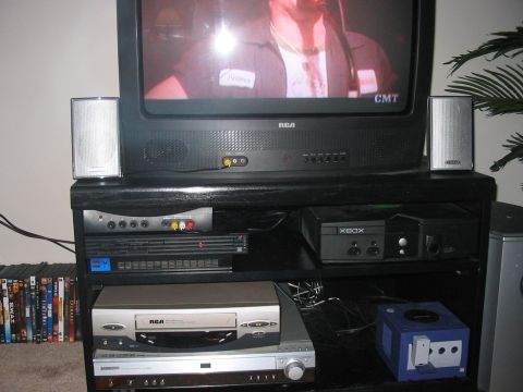 1988 Ford Bronco - A collection of home entertainment electronics is organized on a black stand beneath a television.
