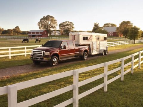 1998 Ford Taurus - Red Ford F-350 Super Duty tows a horse trailer through a rural farm setting with barns and horses in the background.