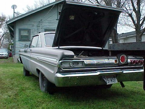 1964 Mercury Comet - The rear of a 1964 Mercury Comet is shown with its hood open, parked on grass in front of a house.