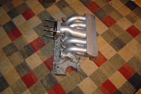 1993 Ford Bronco - Intake manifold with six runners shown on a carpeted surface.