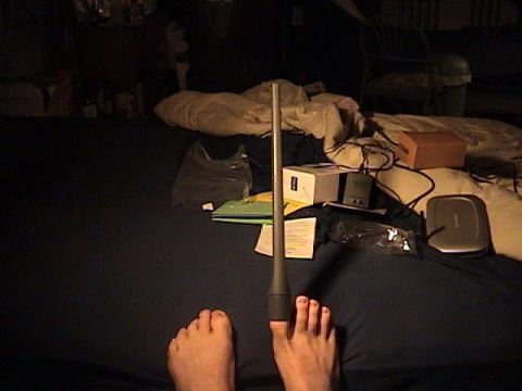 1996 Ford Taurus - A close-up view of feet and a car antenna against a cluttered backdrop.