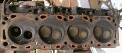 1990 Ford Bronco - Close-up view of an engine cylinder head, showing the combustion chambers and valve openings.