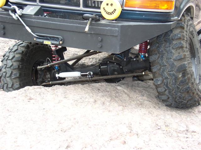 Lifted Ford 4x4 front axle with coil springs, red shocks and steering stabilizer