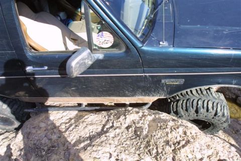 1994 Ford Bronco - 1994 Ford Bronco navigating rocky terrain, front wheel elevated.