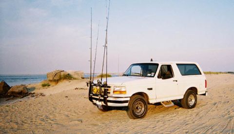 1996 Ford Bronco - This 1996 Ford Bronco is parked on a sandy beach with fishing rods mounted on the front.