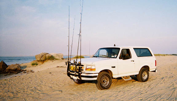 White 1996 Ford Bronco with fishing rod holder on beach