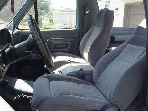 1989 Ford Bronco - Interior view of a Ford truck/SUV showing gray cloth bucket seats, the steering wheel with a black spiral cover, and the dashboard, shot fr…