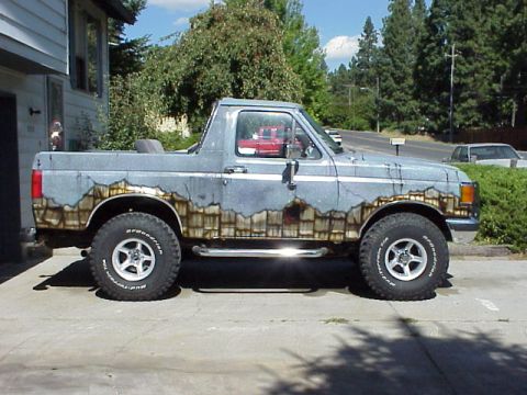 1989 Ford Bronco - This 1989 Ford Bronco features a unique paint job that mimics weathered wood planks and cracked concrete, giving it a distinctive look.