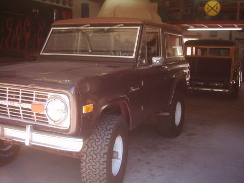 1978 Ford Bronco - A dark brown 1978 Ford Bronco is parked in a garage next to a wood-paneled station wagon.