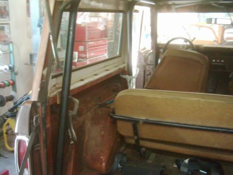 1978 Ford Bronco - Interior view of a 1978 Ford Bronco, showing tan seats and a roll cage, with a workshop visible through the windows.