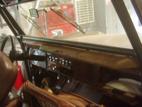 1978 Ford Bronco - The interior of a Ford Bronco, a roll cage, dashboard, and seats, is shown from the driver's perspective.
