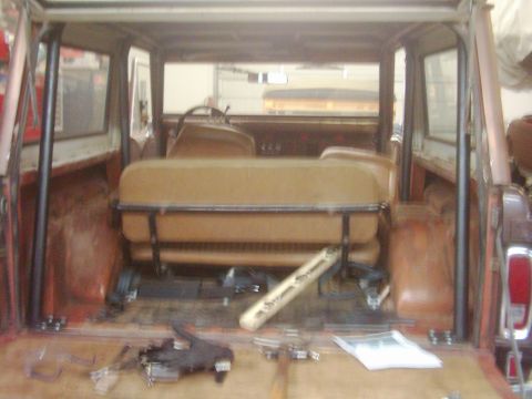 1978 Ford Bronco - The interior of a 1978 Ford Bronco shows tan seats, a roll cage, and the cargo area with various tools and parts.
