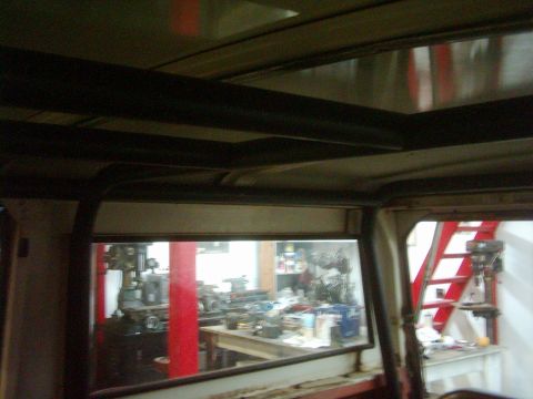 1978 Ford Bronco - Interior view of a vehicle with a roll cage, looking out into a workshop with machinery and machinery.
