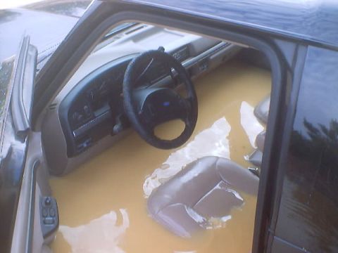 1995 Ford Bronco - The interior of a vehicle is filled with brown water, submerging the seats and dashboard.