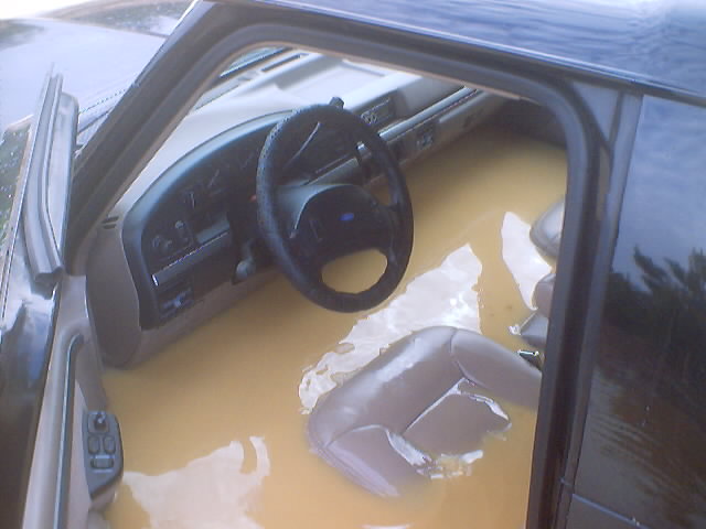 Car interior submerged in murky water, seats and dashboard visible