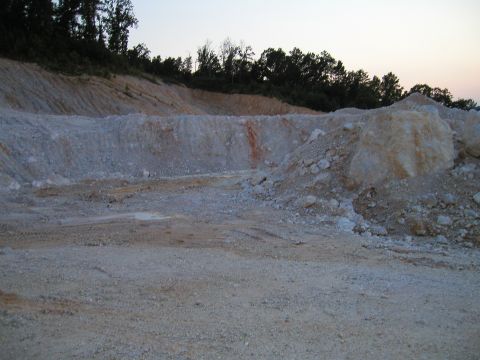 1989 Ford Bronco - A quarry scene with piles of dirt and rocks, bordered by trees at dusk.