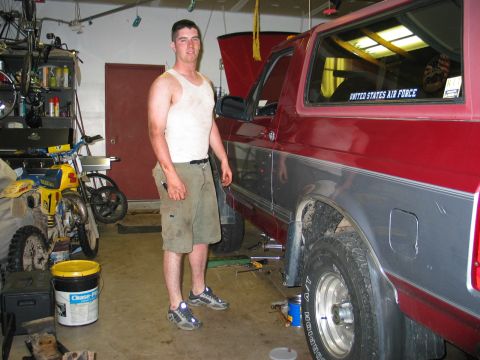 1995 Ford Bronco - A man stands in a garage next to a red and grey SUV, with tools and a motorcycle visible in the background.