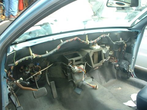 1999 Ford Crown Victoria - The dashboard of a car is disassembled, revealing a complex network of wires and electrical components.
