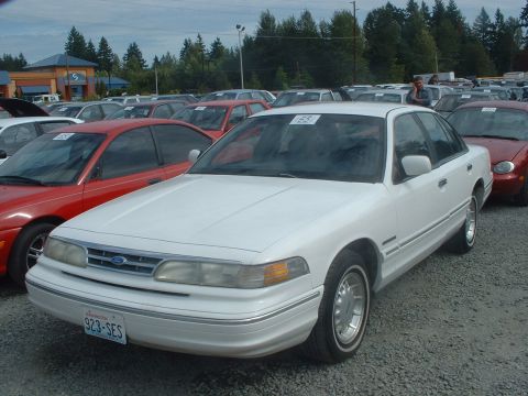 1999 Ford Crown Victoria - White 1999 Ford Crown Victoria sedan in a car lot with other vehicles visible.