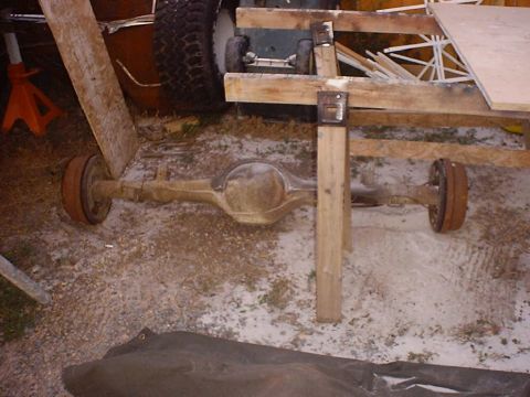 1988 Ford Bronco - A rear axle assembly, likely from a truck or SUV, is shown disassembled and supported by makeshift wooden scaffolding.