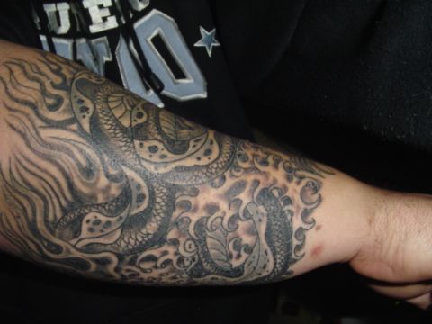 1993 Ford Bronco - A detailed tattoo covers an arm, depicting a dragon amidst swirling waves.