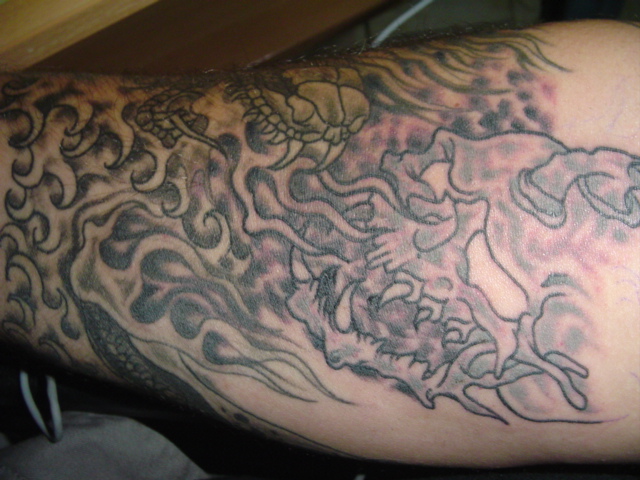 Tattoo of a dragon with waves and a turtle