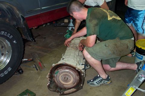 1995 Ford Bronco - Mechanics work on a removed transmission, possibly from a 1995 Ford Bronco.