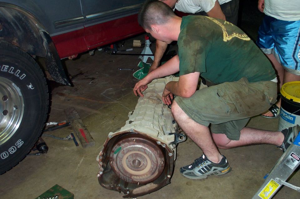 Transmission removed from vehicle, being worked on by mechanics