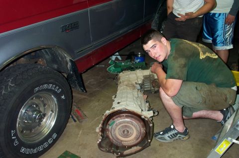 1995 Ford Bronco - A man works on a removed transmission from a Ford Bronco XLT in a garage setting.