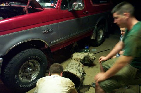 1995 Ford Bronco - A red and gray Ford Bronco is being worked on, with its transmission removed and placed on the ground.
