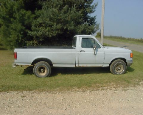 1985 Ford F-150 - This pickup truck appears to be a Ford F-150, likely from the late 1980s, parked on grass.