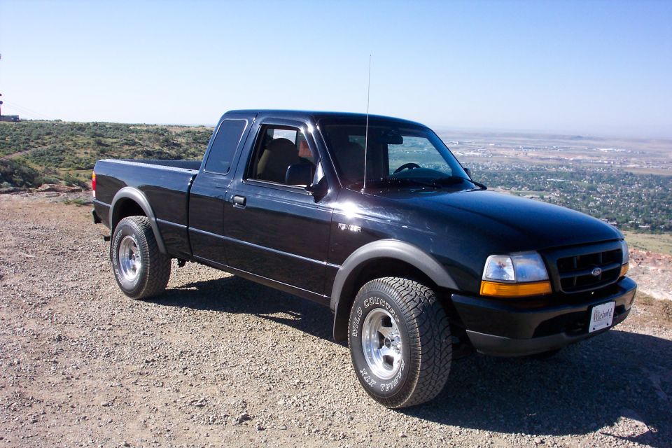 Black Ford Ranger extended-cab 4x4 on a gravel overlook above a valley