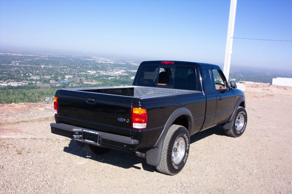 Black 1999 Ford Ranger pickup truck parked on a hill overlooking a city