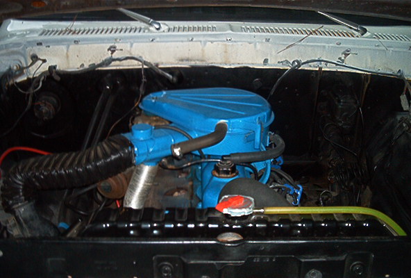 Engine bay with a blue-painted V8 air cleaner under an open white hood
